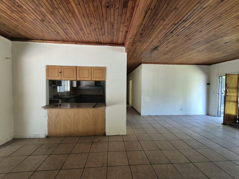 Open plan living area featuring a timber ceiling, tiled flooring, and a kitchen pass-through with a built-in breakfast counter.