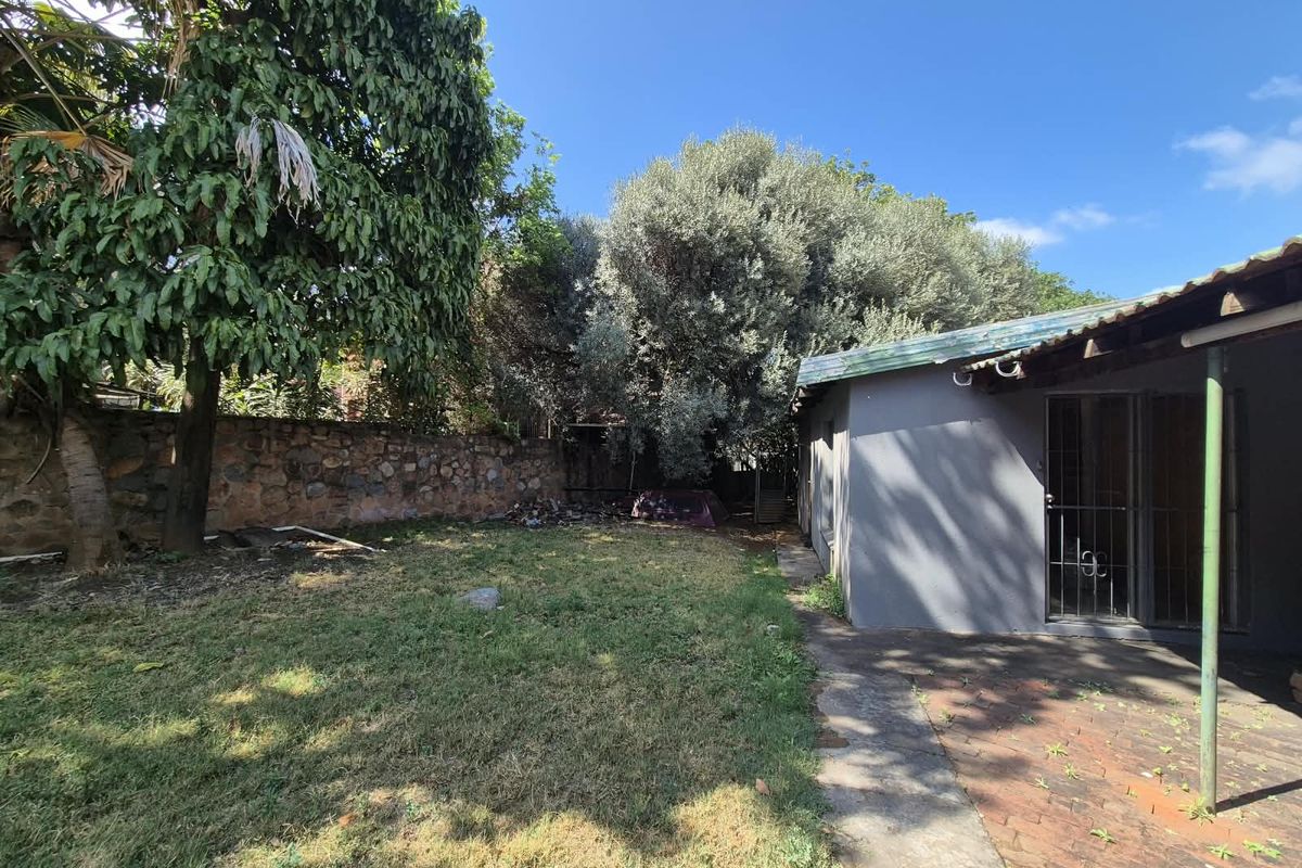 Rear garden area featuring a brick paved patio, stone boundary wall, and established trees, providing a private outdoor space.