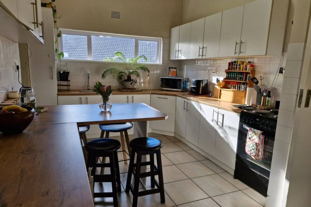 A functional kitchen featuring white cabinetry, wooden countertops, tiled backsplash, and a built-in oven with a breakfast nook area.
