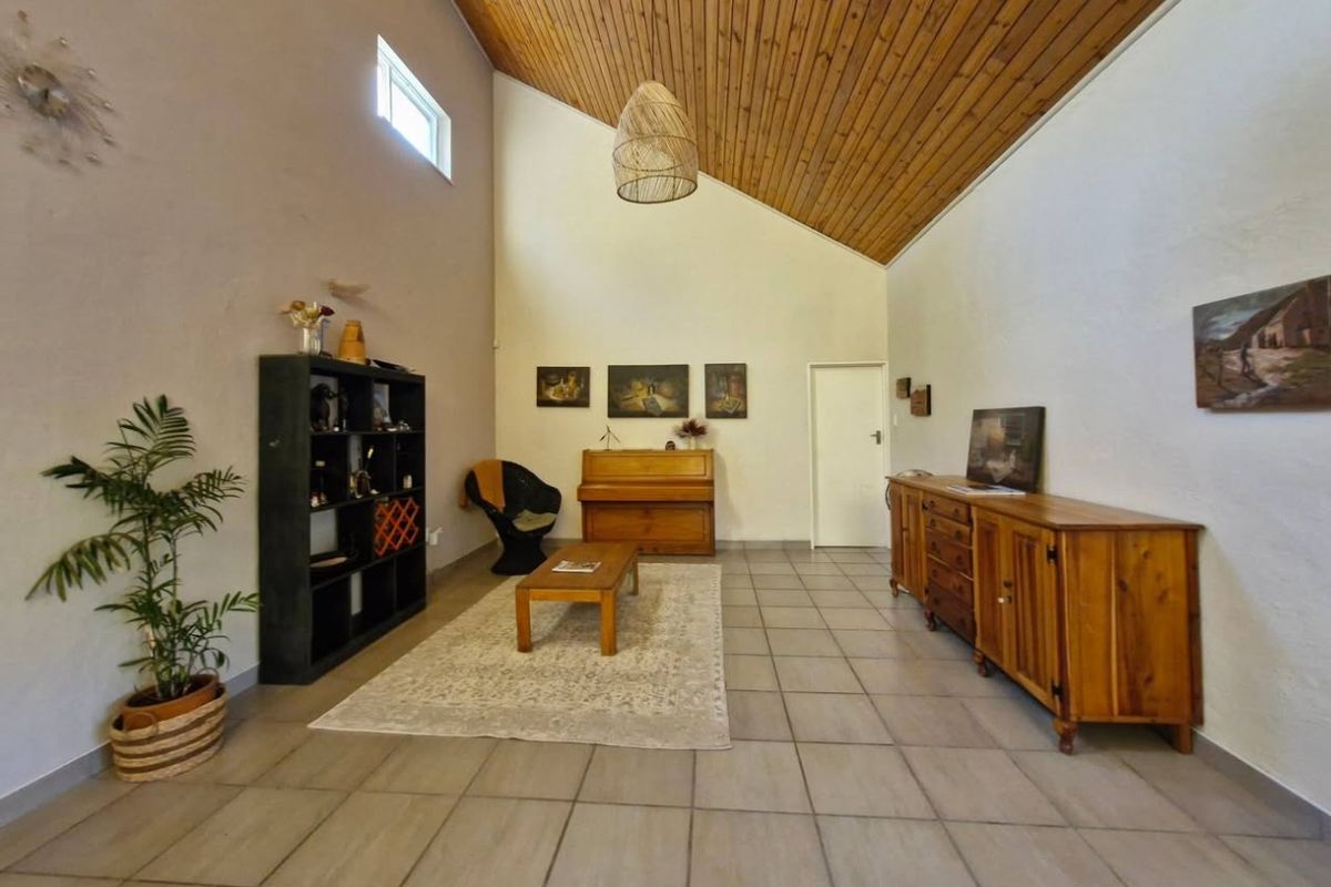 Spacious living room featuring a high vaulted timber ceiling, neutral walls, and tiled flooring, offering a bright and airy atmosphere.