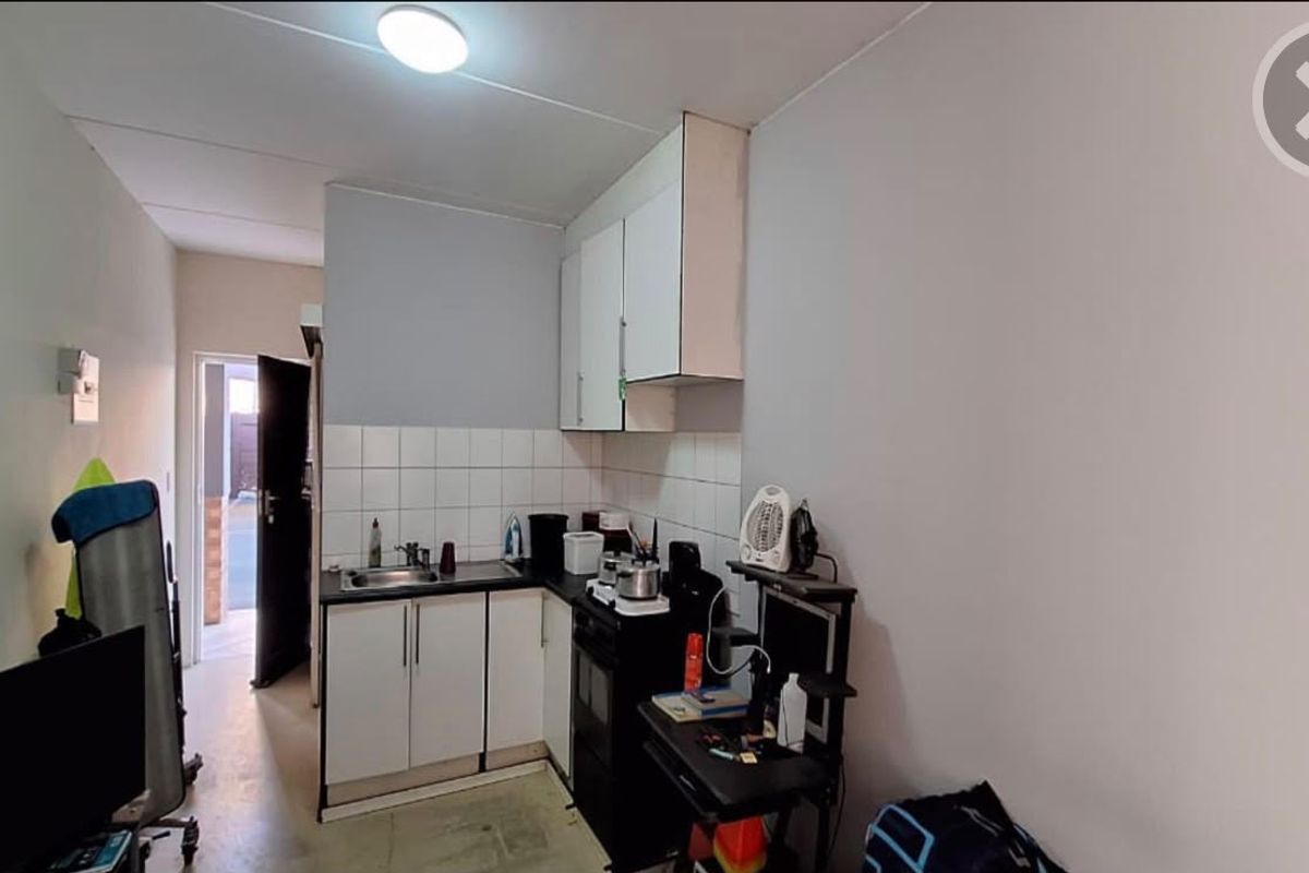 Compact kitchen area featuring built-in cabinetry, a stainless steel sink, and tiled splashback, providing essential functionality in a modest footprint.