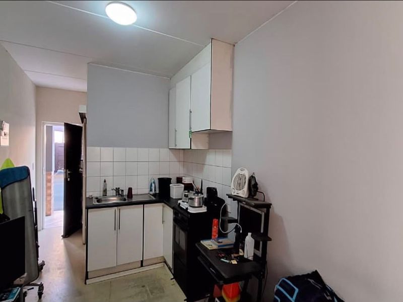 Compact kitchen area featuring built-in cabinetry, a stainless steel sink, and tiled splashback, providing essential functionality in a modest footprint.