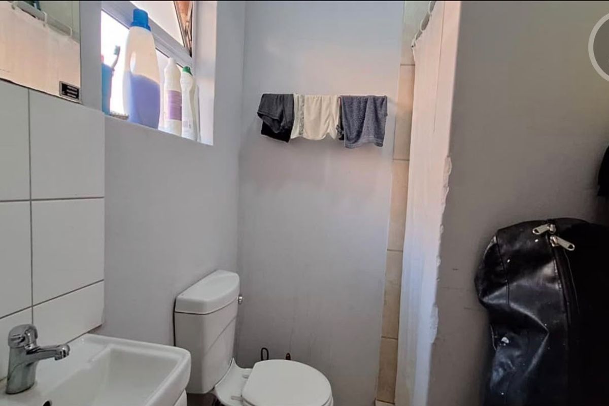 A compact bathroom featuring a standard toilet, washbasin with faucet, and a shower area with a curtain.