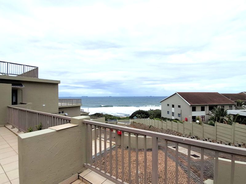 Spacious balcony featuring tiled flooring and metal balustrades, offering an elevated view of the surrounding neighborhood and the ocean.