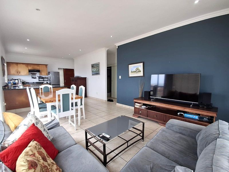Open-plan living and dining area featuring tiled floors, recessed lighting, and a functional kitchen with built-in cabinetry and an extractor fan.