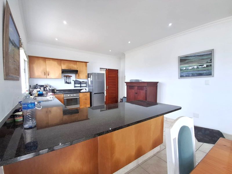 A functional kitchen featuring wooden cabinetry, granite countertops, a built-in oven, and recessed lighting, offering a practical layout for daily meal preparation.