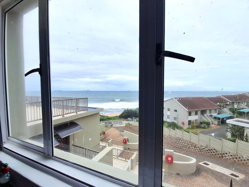 A view from an apartment window overlooking the coastal estate, surrounding buildings, and the ocean horizon.