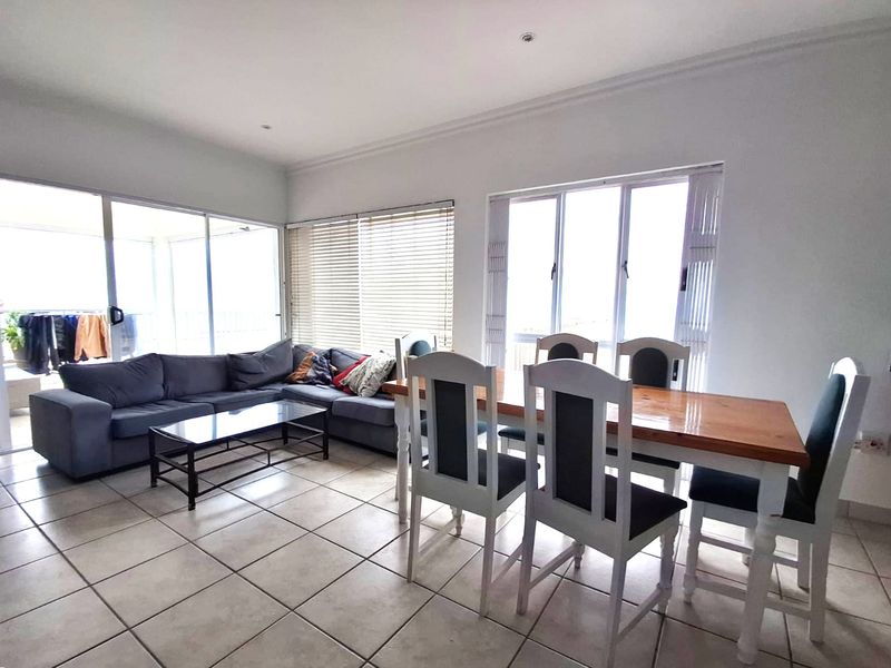 Spacious open-plan living and dining area featuring large windows, tiled flooring, and sliding glass doors leading to an outdoor space.