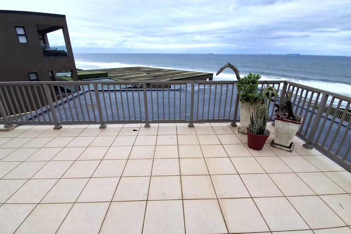 Spacious balcony featuring tiled flooring and a metal balustrade, offering expansive ocean views.