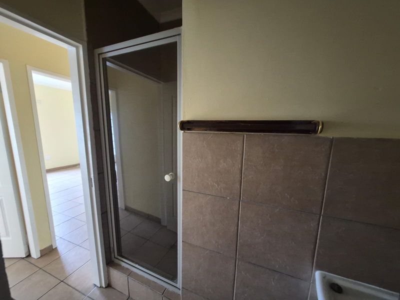 A bathroom interior featuring a shower enclosure with tiled walls and a wall-mounted towel rail.