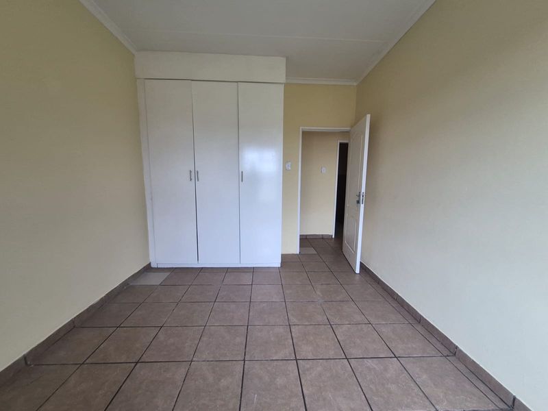 An empty bedroom featuring tiled flooring and built-in cupboards, offering a clean and neutral space ready for personalization.