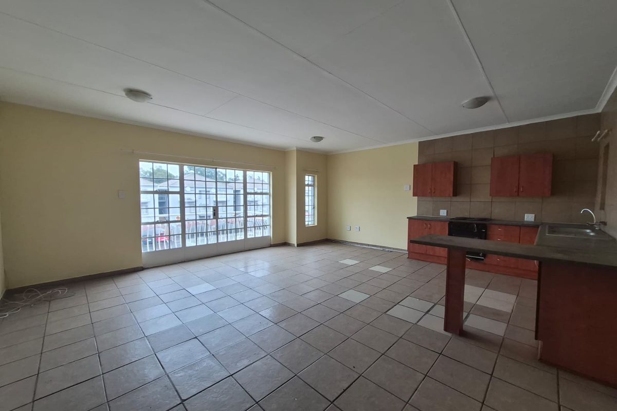 Spacious open-plan living and kitchen area featuring tiled flooring, built-in cabinetry, and a sliding glass door leading to an outdoor space.