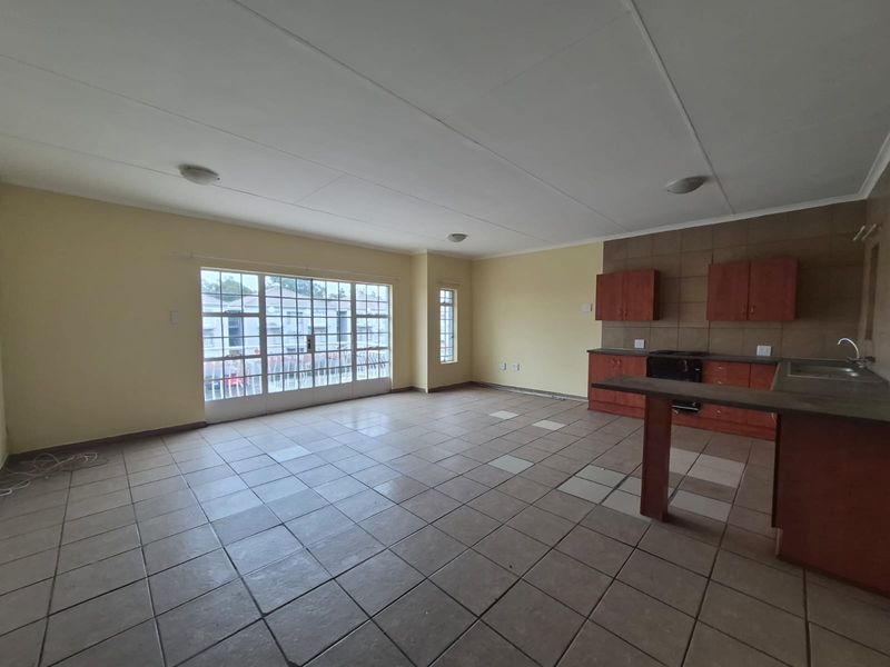 Spacious open-plan living and kitchen area featuring tiled flooring, built-in cabinetry, and a sliding glass door leading to an outdoor space.