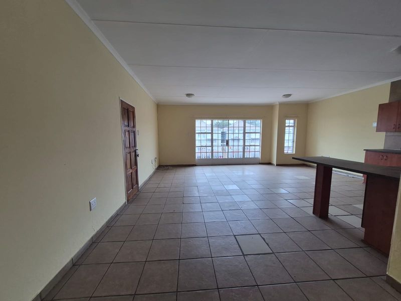 Spacious open-plan living area featuring tiled flooring, a built-in breakfast bar, and large sliding glass doors providing natural light.