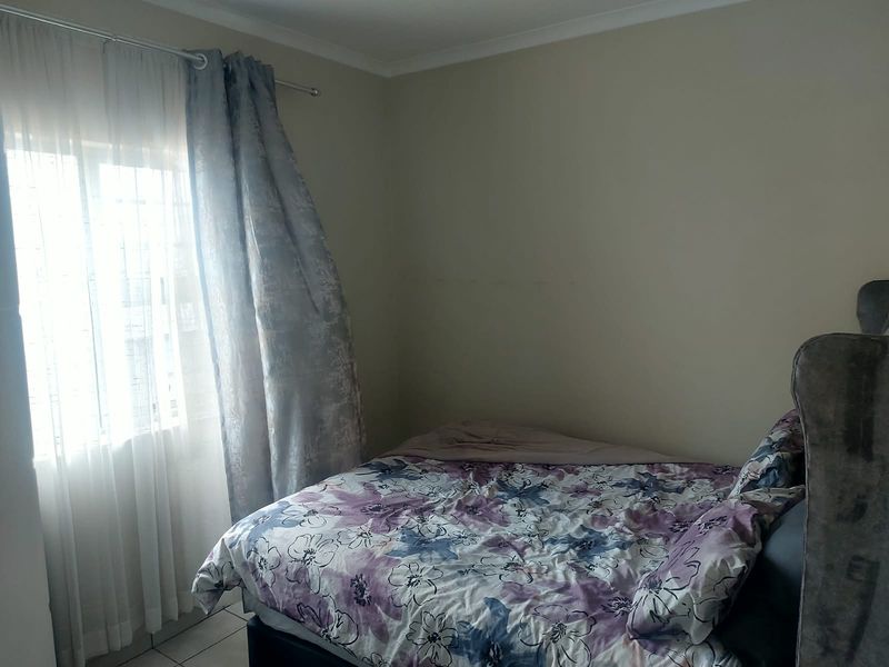 A standard bedroom featuring tiled flooring and a window with installed curtain rods, providing a functional living space.