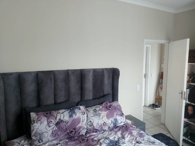 A neutrally painted bedroom featuring coving and access to an adjoining tiled hallway.
