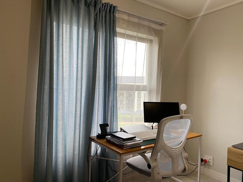 A functional home office space featuring a window with curtains, providing natural light and a view of the surrounding area.
