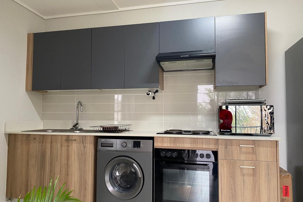Modern kitchen featuring two-tone cabinetry, integrated oven and hob, extractor fan, tiled backsplash, and a built-in washing machine.