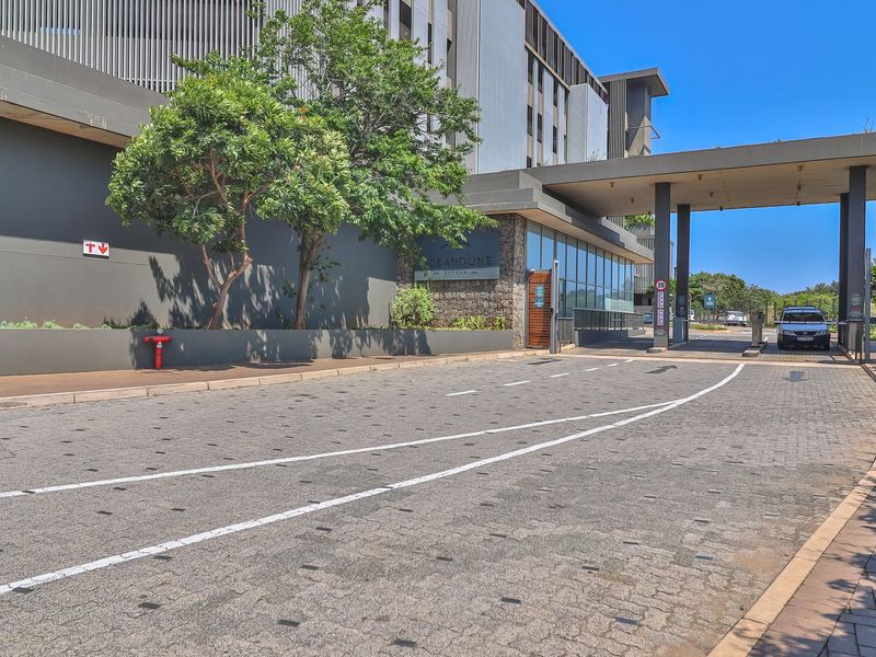 The entrance to the Oceandune complex features a modern security gatehouse, paved driveway, and contemporary architectural finishes with stone cladding and concrete pillars.
