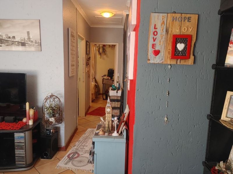 A view of an interior hallway with tiled flooring and textured wall finishes, leading towards an adjacent room.