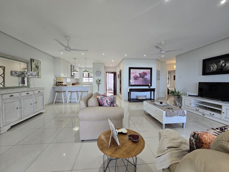 Spacious open-plan living area featuring polished porcelain floor tiles, recessed lighting, ceiling fans, and a modern kitchen with a central island.