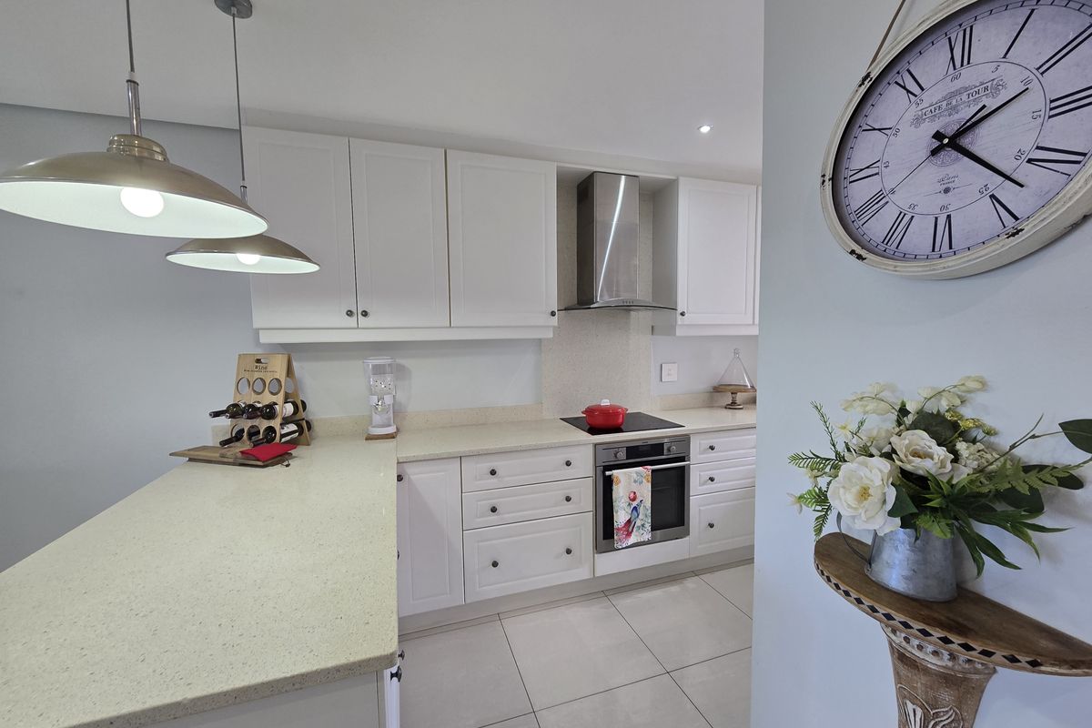 Modern kitchen featuring white cabinetry, stone countertops, stainless steel appliances, and tiled flooring, offering a clean and functional cooking space.