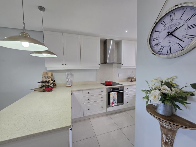 Modern kitchen featuring white cabinetry, stone countertops, stainless steel appliances, and tiled flooring, offering a clean and functional cooking space.