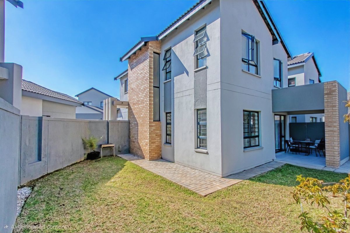 Rear view of a double-storey cluster home featuring a paved patio area, landscaped garden, and modern brick and plaster exterior finishes.