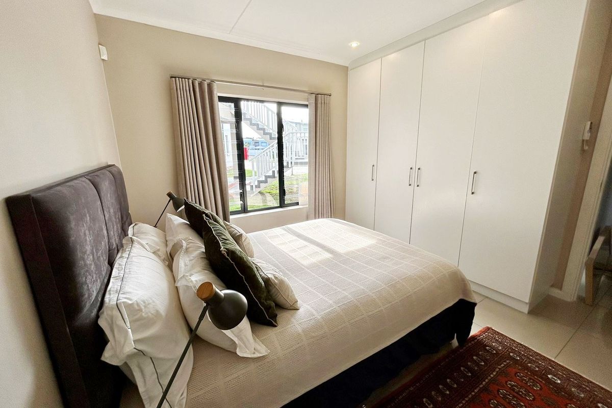 A well-maintained bedroom featuring neutral walls, tiled flooring, recessed downlighting, and ample built-in cupboard storage.