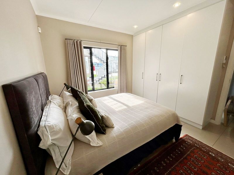 A well-maintained bedroom featuring neutral walls, tiled flooring, recessed downlighting, and ample built-in cupboard storage.