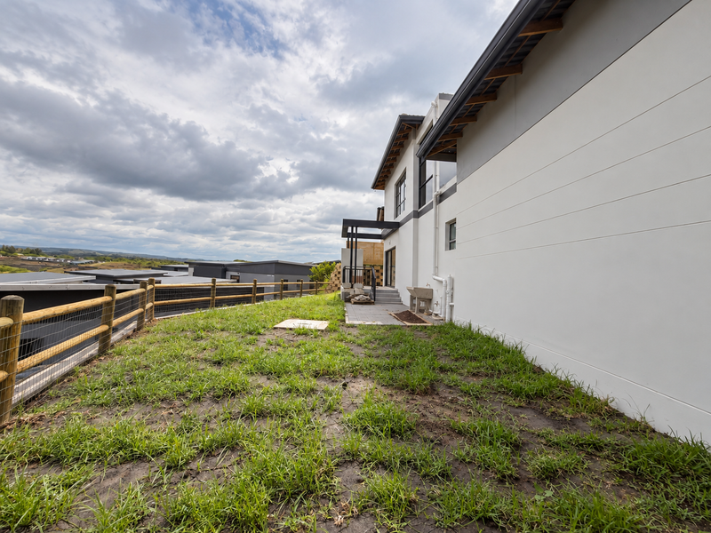 Rear exterior view of the property featuring a paved patio, utility sink, and a large unfinished garden area enclosed by a timber fence.