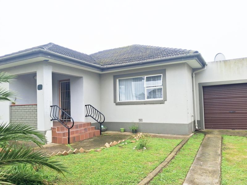 Front elevation of a single-story house featuring a tiled roof, attached garage with roller door, and a paved entrance with security gate.