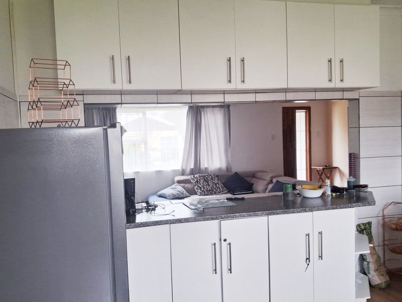 Open plan kitchen area featuring white built-in cabinetry and a functional breakfast bar overlooking the living space.