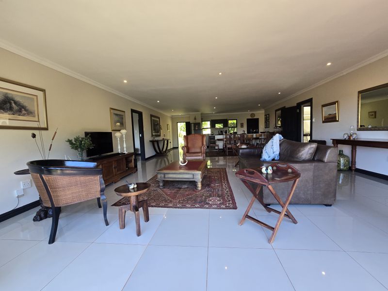 Spacious open-plan living area featuring large format floor tiles and recessed downlighting, seamlessly connecting the lounge and kitchen spaces.