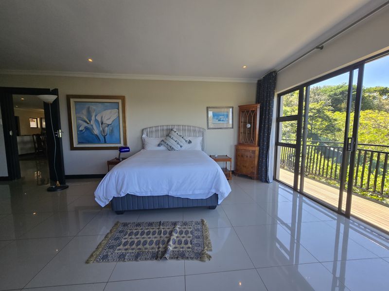 Spacious bedroom featuring large sliding glass doors leading to a balcony, polished tiled flooring, and recessed lighting.