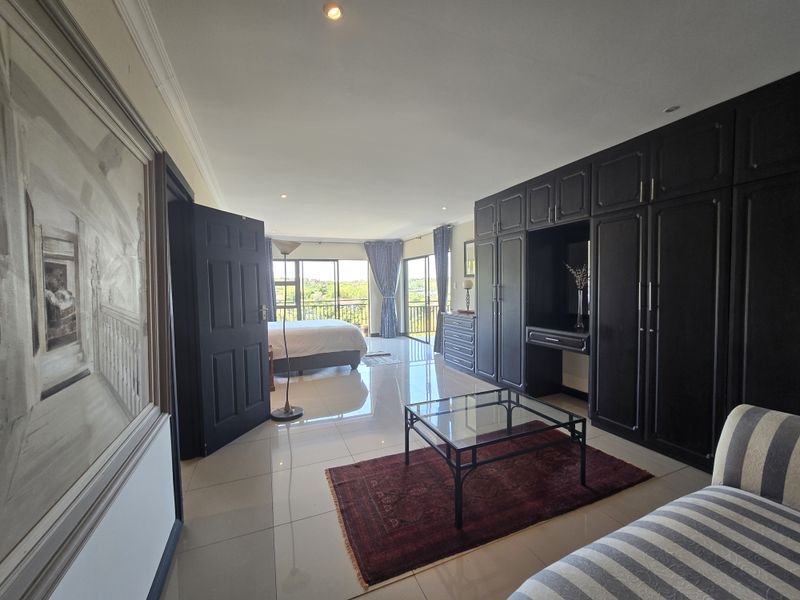 Spacious bedroom featuring large built-in cupboards, polished tiled flooring, and sliding glass doors leading to a private balcony with scenic views.