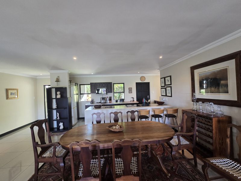 An open-plan living and dining area featuring a kitchen with a central island, tiled flooring, and recessed lighting, creating a functional family space.