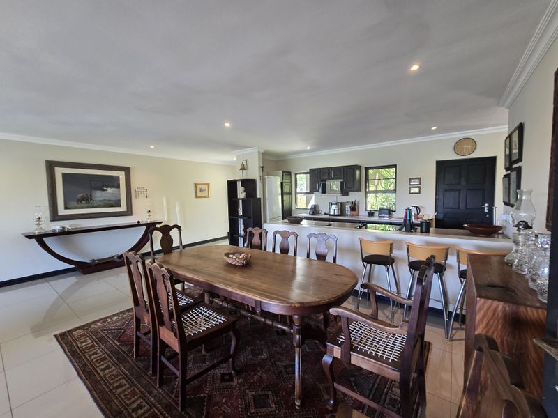 Spacious open-plan living and dining area featuring a functional kitchen with dark cabinetry, a breakfast bar, and tiled flooring throughout.