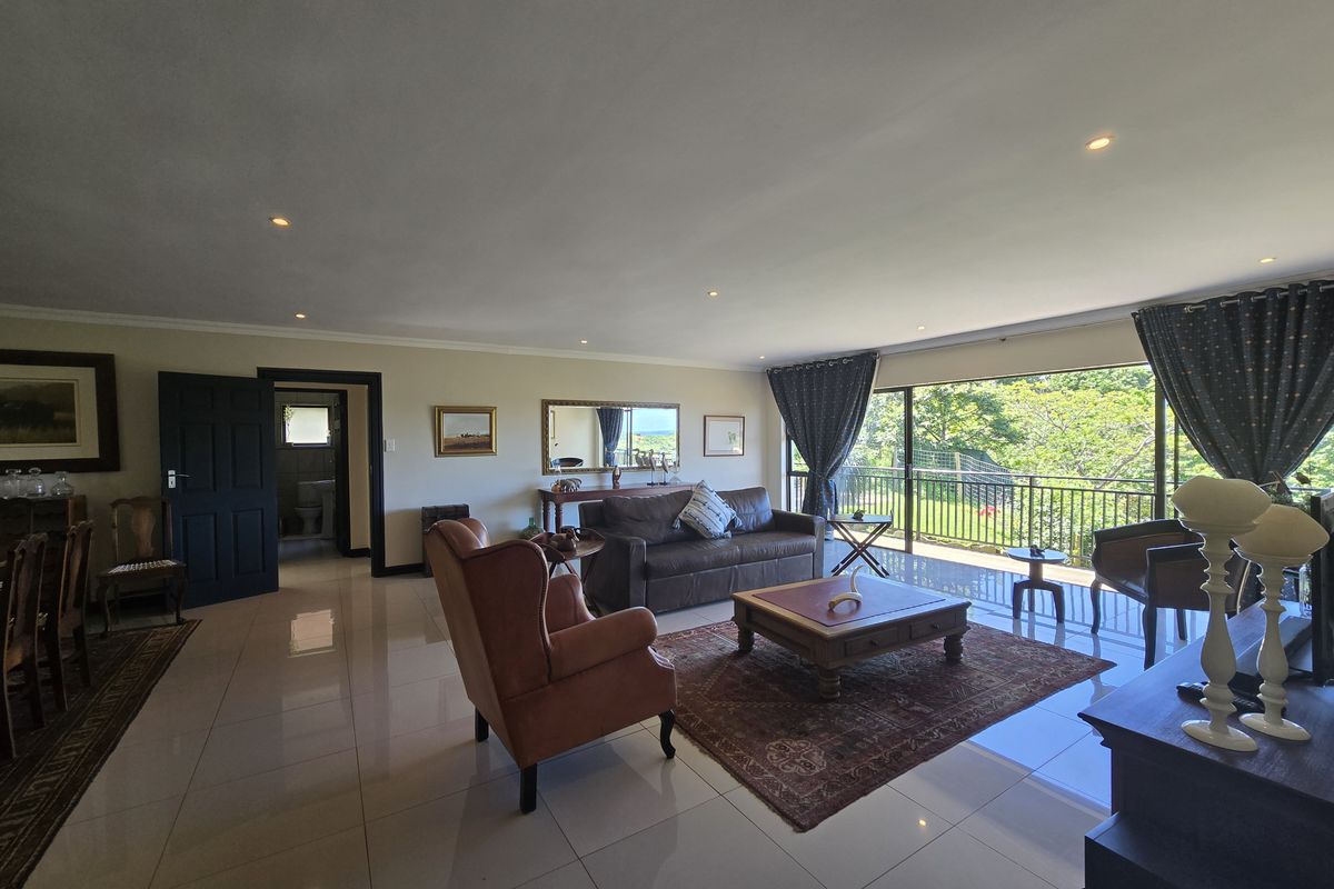 Spacious living room featuring polished tiled flooring, recessed downlighting, and large sliding glass doors that open onto a balcony with scenic views.