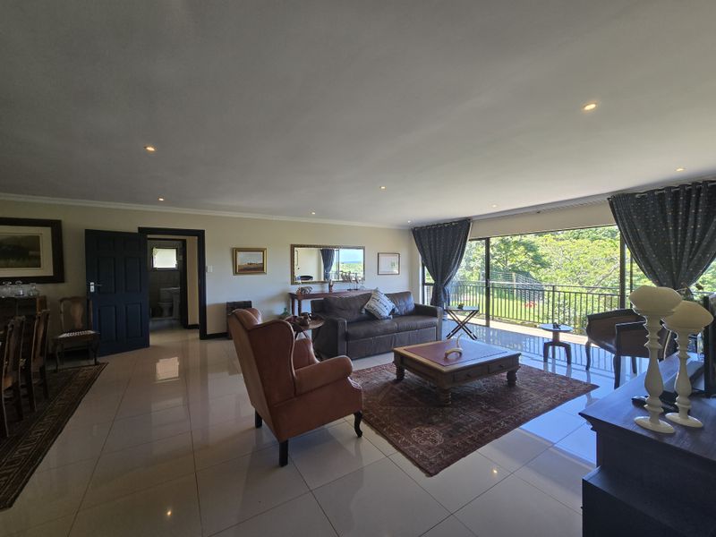 Spacious living room featuring polished tiled flooring, recessed downlighting, and large sliding glass doors that open onto a balcony with scenic views.