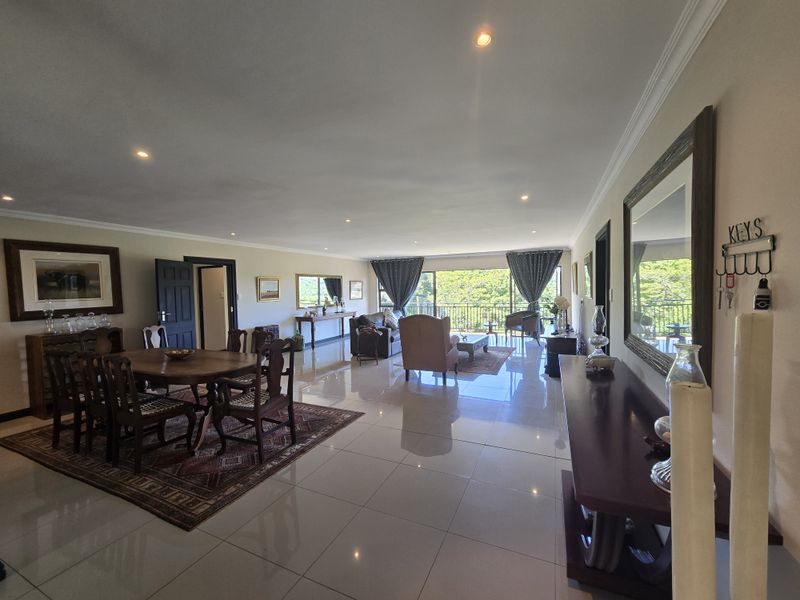 Spacious open-plan living and dining area featuring polished porcelain floor tiles, recessed lighting, and large sliding doors leading to an outdoor balcony.