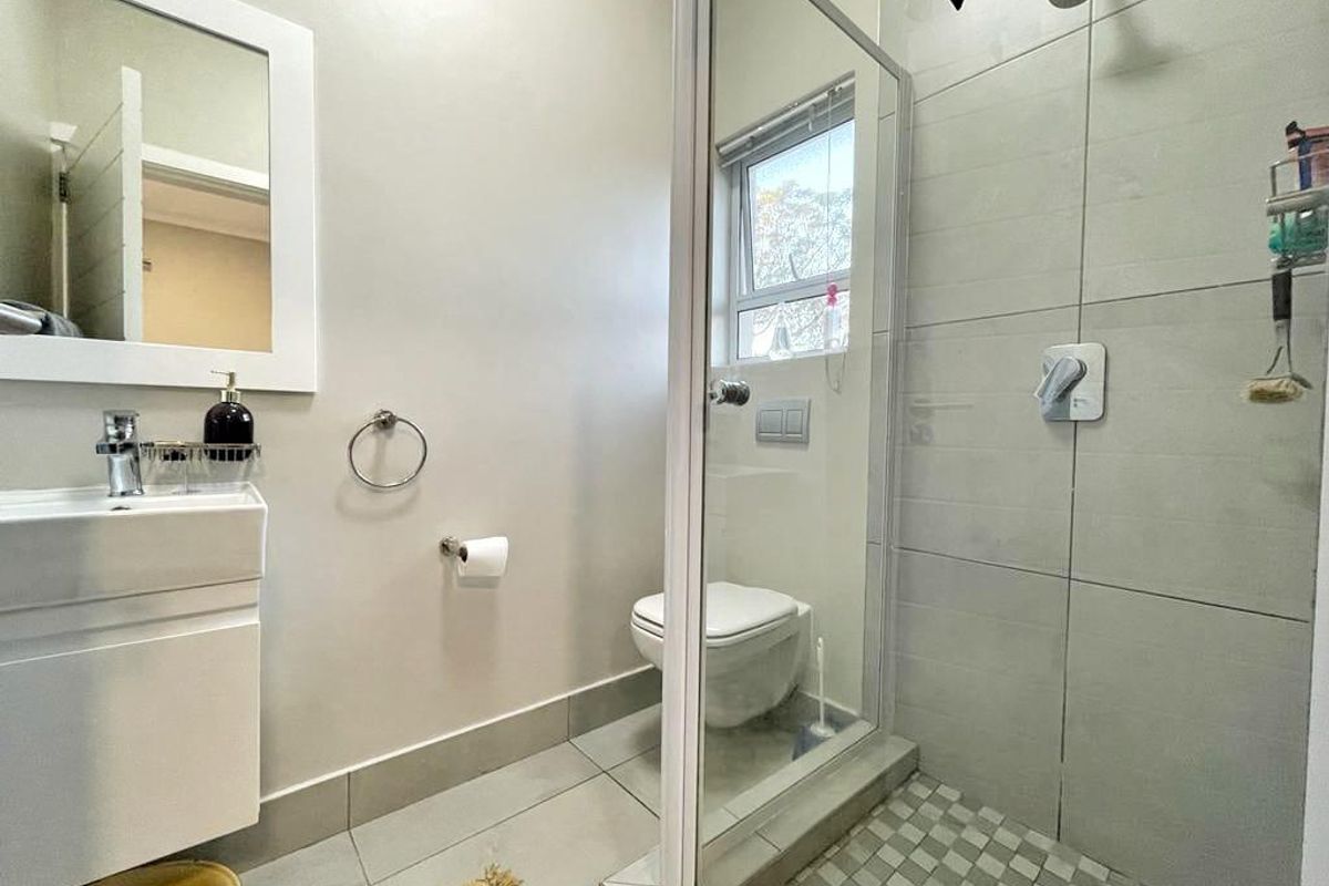 A clean and functional bathroom featuring a modern vanity, a glass-enclosed shower with tiled walls, and a wall-mounted toilet.
