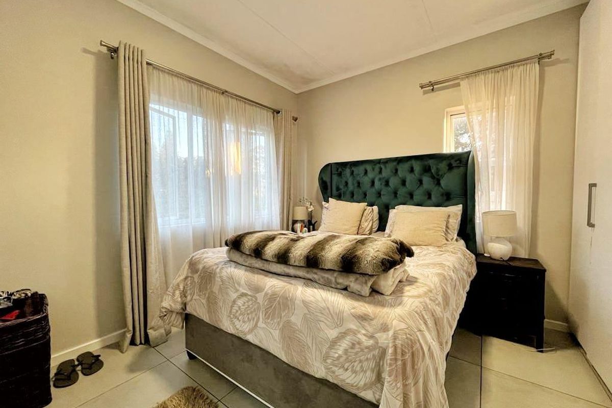 A well-lit bedroom featuring tiled flooring, neutral wall finishes, and a built-in wardrobe, offering a comfortable and functional living space.