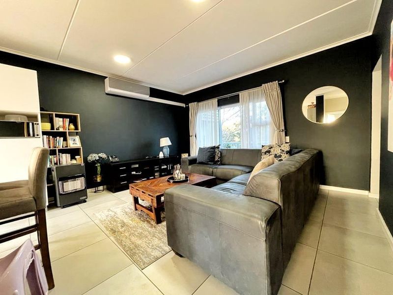 A well-maintained living room featuring tiled flooring, recessed lighting, and a wall-mounted split-system air conditioner, providing a comfortable and functional living space.