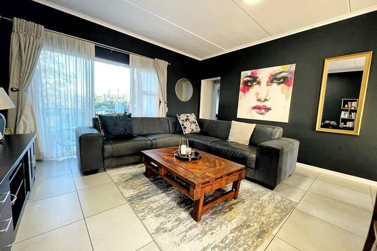 A well-maintained living room featuring large format floor tiles, dark accent walls, and a sliding glass door providing access to an outdoor area.