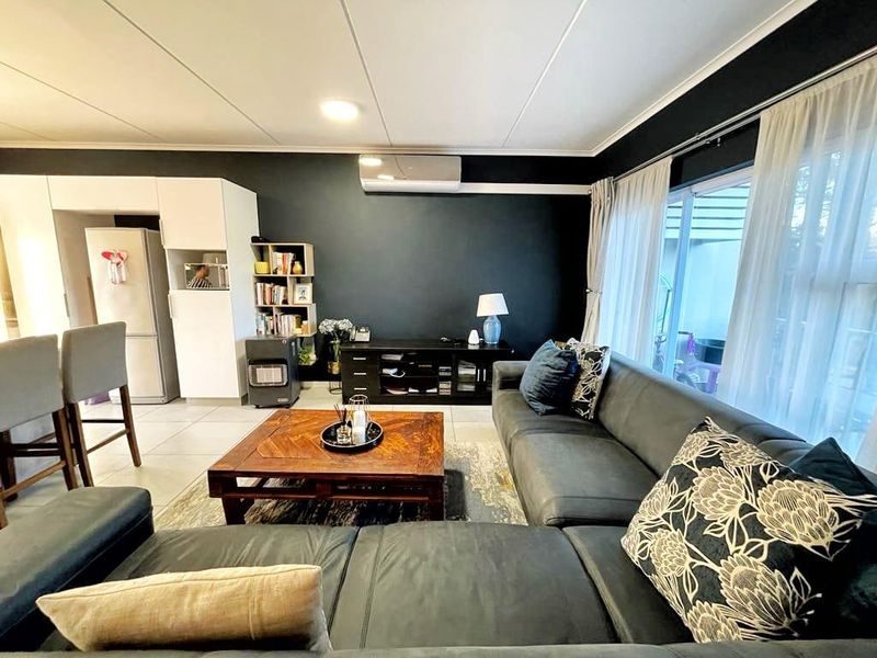 An open-plan living area featuring tiled flooring, a split-system air conditioner, and large sliding glass doors providing access to the outdoor space.