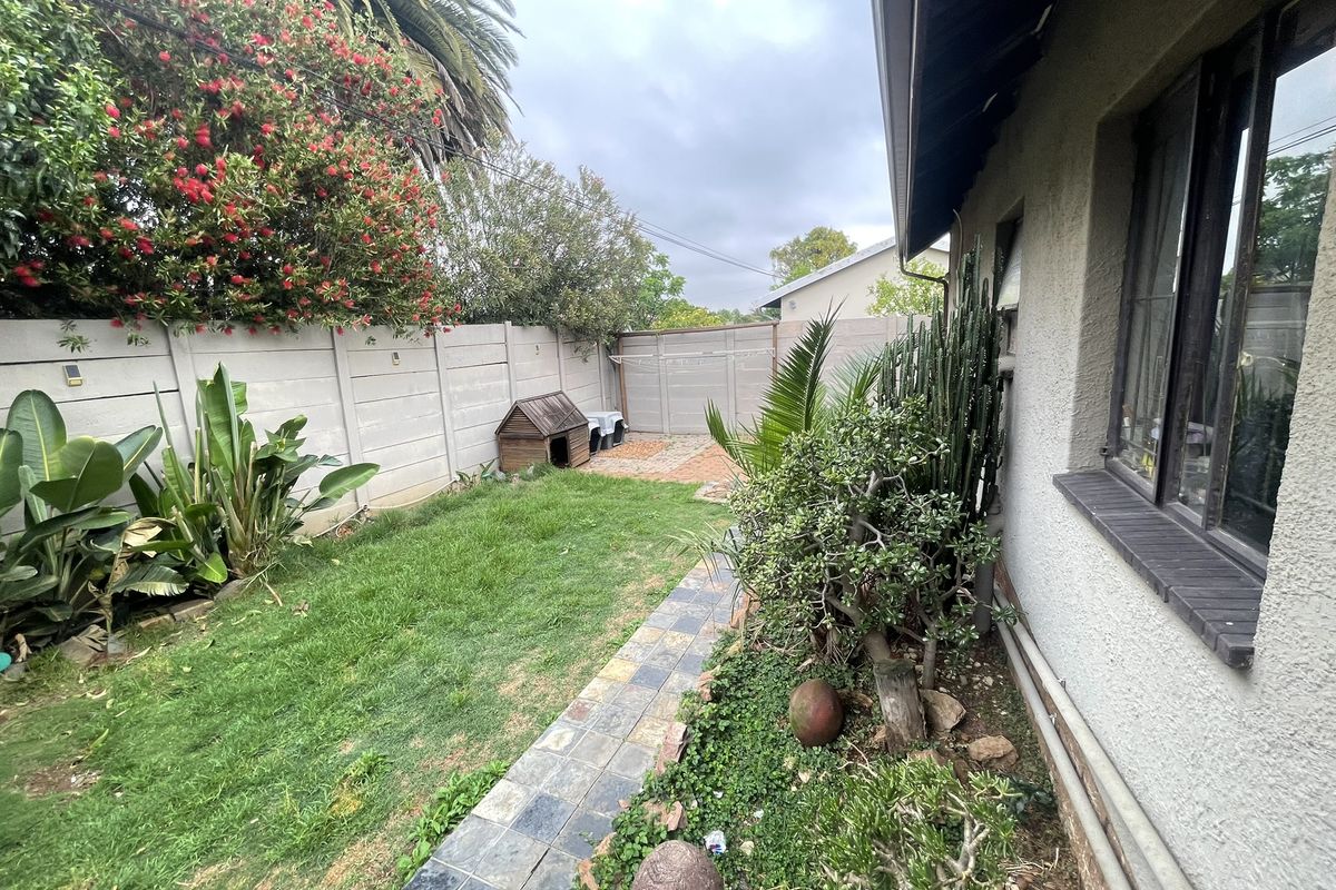 A private rear garden featuring a lawn, paved walkway, and secure precast concrete boundary walls.