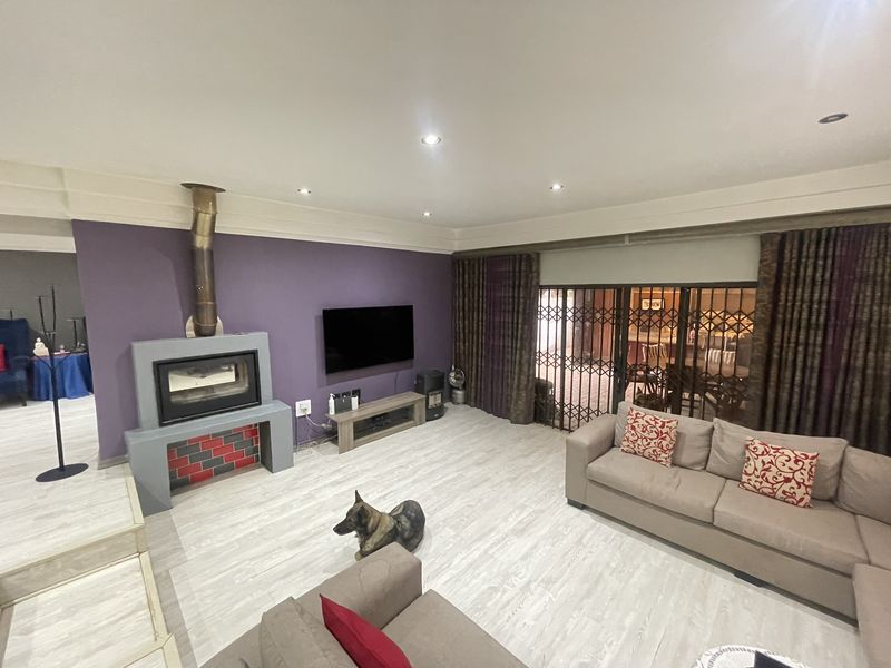 Spacious living room featuring a built-in fireplace, modern laminate flooring, recessed lighting, and large sliding doors with security gates leading to the patio.