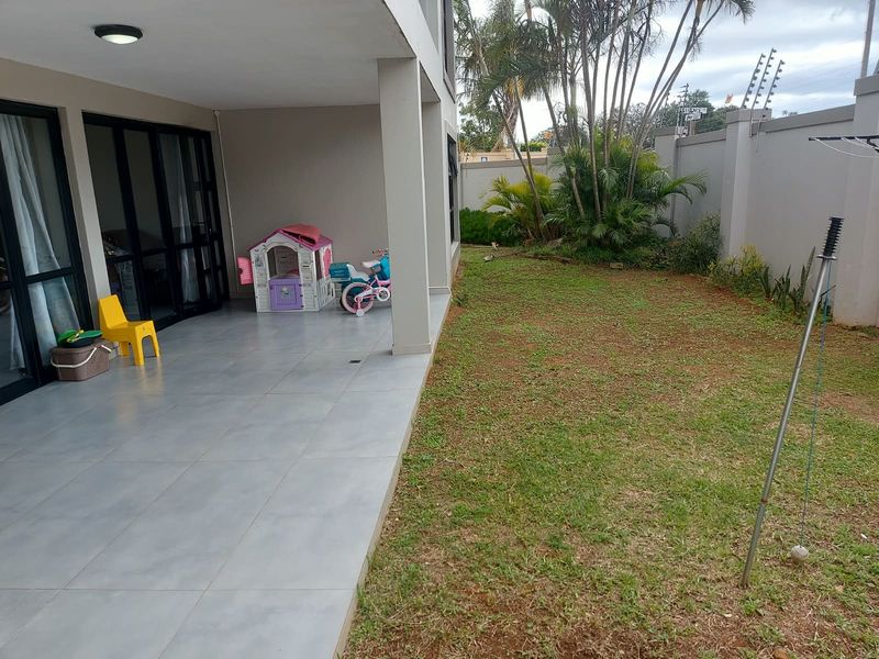 A covered patio area with tiled flooring, providing seamless access to the rear garden and perimeter wall.