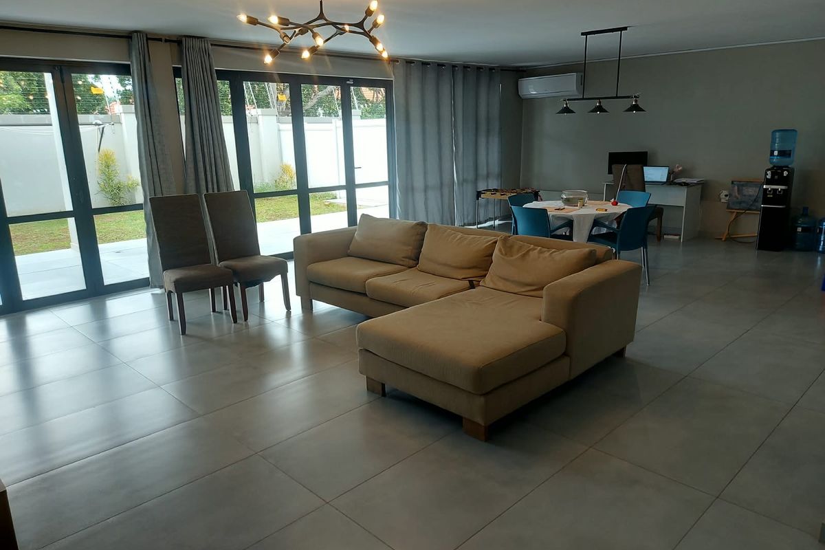 Spacious living area featuring large format floor tiles, modern lighting, and expansive aluminium sliding doors providing direct access to the outdoor area.